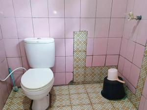 ein Badezimmer mit Toilette und rosa gefliester Wand in der Unterkunft BATUKARAS Orchid Homestay in Batukaras