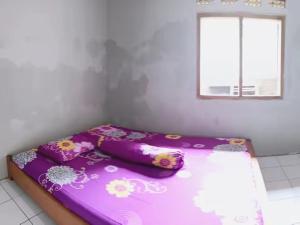 ein violettes Bett in einem Zimmer mit Fenster in der Unterkunft BATUKARAS Orchid Homestay in Batukaras + 12 Fotos