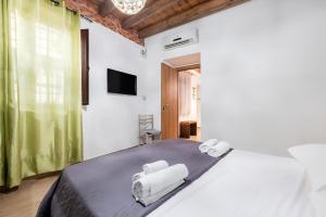 a bedroom with a large white bed with two towels at Damiani Appartamenti nel Centro Storico di Palermo in Palermo