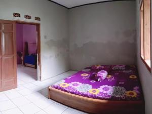 a bedroom with a purple bed with flowers on it at BATUKARAS Orchid Homestay in Batukaras