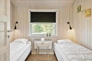 a small bedroom with two beds and a window at LF10210-Thyholm-Skovstien-10 in Thyholm