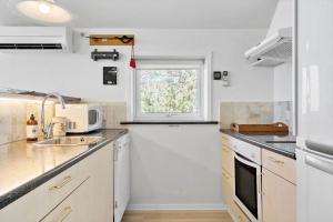 a white kitchen with a sink and a window at LF10229-Thyholm-Skovstjernevej-9 in Thyholm +17 photos