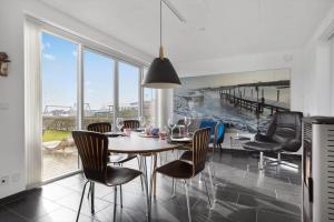 a dining room with a table and chairs and a large window at LF10214-Thyholm-Havnefronten-14 in Thyholm
