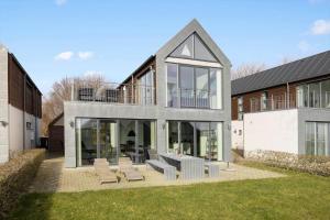 a house with glass doors and chairs in a yard at LF10214-Thyholm-Havnefronten-14 in Thyholm