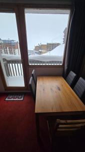 een houten tafel in een kamer met 2 grote ramen bij Val Thorens Centre, Kino Duplex, 34m2, 5-6 personnes in Val Thorens