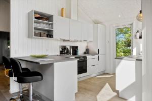 een keuken met witte kasten en een aanrecht met stoelen bij LF11106-Struer-Slugten-6 in Humlum +10 foto's