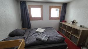 een slaapkamer met een bed en twee ramen bij Val Thorens Centre, Kino Duplex, 34m2, 5-6 personnes in Val Thorens