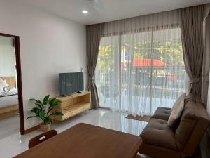 un salon avec un canapé, une table et une télévision dans l'établissement Sunsea Resort, à Baan Khai