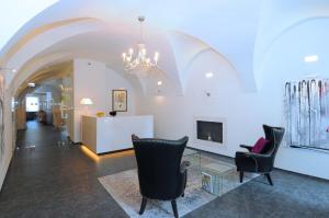 a lobby with chairs and a fireplace and a chandelier at Hotel Kramer in Opava