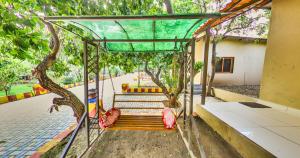 a swing in front of a building with trees at Tejas Gir Villas in Sasan Gir