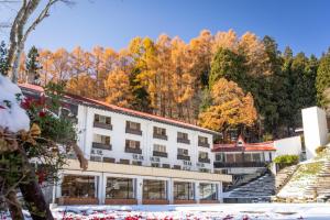 ein Hotel mit Herbstlaub im Hintergrund in der Unterkunft Nozawa Grand Hotel in Nozawa Onsen