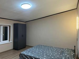 a bedroom with a bed and a black cabinet at Дачный дом in Balqash