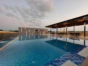 Kampong KiulapJ HOTEL的大楼前的蓝色海水大型游泳池