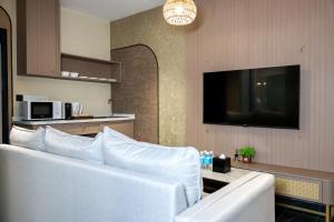 a living room with a white couch and a tv at Kivana Suite, Vetro 11 by Ayuhouz in Kota Kinabalu