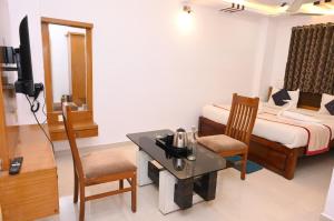 a hotel room with a bed and a table and chairs at Hotel Kailash Heaven in Madikeri +17 photos