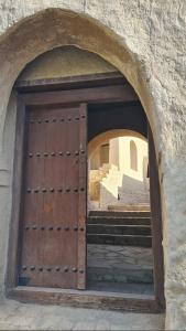 a wooden door in a stone building with stairs at سمارا أدم SAMARA Adam in Ādam