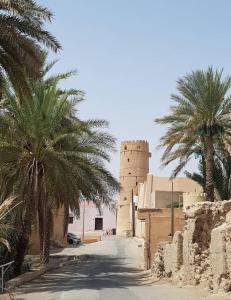 a street with palm trees and a building with a tower at سمارا أدم SAMARA Adam in Ādam