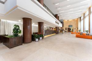 a lobby with orange furniture and plants in a building at Good East Hotel in Guangzhou
