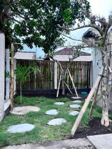 een tuin met stenen in het gras en een hek bij The Inside House Medewi in Airsatang