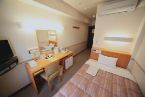 土浦市にあるCrown Hills Tsuchiuraekihigashiの小さな客室で、デスク、ベッド、鏡が備わります。
