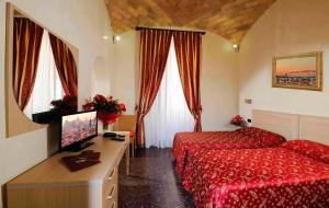 ローマにあるHotel Campidoglioのベッド、デスク、テレビが備わるホテルルームです。