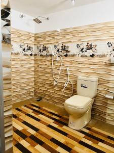 a bathroom with a toilet and a wooden wall at Azure Coast Villa in Ahangama