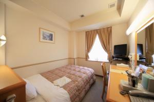 土浦市にあるCrown Hills Tsuchiuraekihigashiのベッド、デスク、コンピュータが備わるホテルルームです。