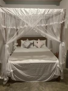 a bed with a canopy with white sheets and pillows at Calm Villa in Mihiripenne