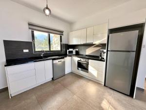 een grote keuken met witte kasten en een raam bij Retreat, block A2, unit 1 in Ayios Nikolaos