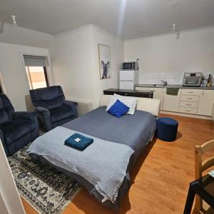 een slaapkamer met een bed en 2 stoelen en een keuken bij Fauna Australia Wildlife Experience in Lavers Hill