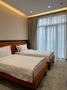 a hotel room with two beds and a window at Afrosiyob Regency Hotel in Stantsiya Kyzyl-Tukumachi