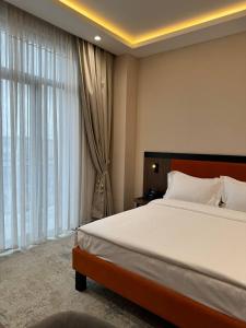 a bedroom with a large bed and a large window at Afrosiyob Regency Hotel in Stantsiya Kyzyl-Tukumachi