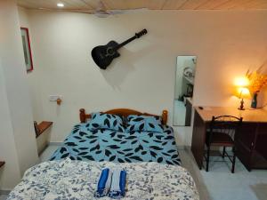a bedroom with a bed and a guitar on the wall at Ebony Room - AC, Kitchenette, Ensuite, Independent Homestay in Mumbai