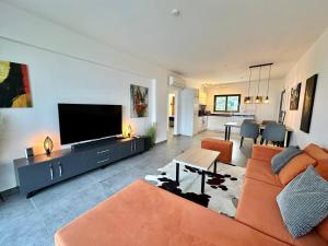 een woonkamer met een oranje bank en een flatscreen-tv bij Retreat block A2, unit 6 in Küçükerenköy