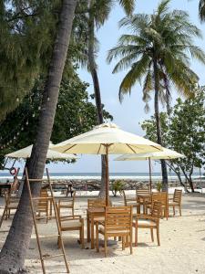 een groep stoelen en parasols op een strand bij TWIN PALMS 'Beach House' - New surf front location in Thulusdhoo +22 foto's