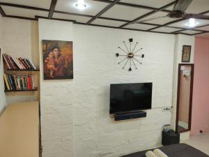 a wall with a tv and a clock on it at Ivory Room, AC, Smart TV, Ensuite, Independent Homestay in Mumbai