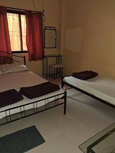 two beds sitting in a room with a window at Hotel Cosy Nook in Malvan