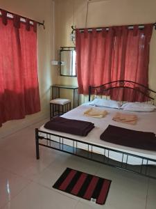a bedroom with a large bed with a red curtain at Hotel Cosy Nook in Malvan