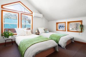 two beds in a room with two windows at Chalet GOROU in Hakuba