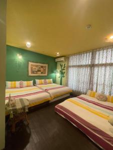 2 Betten in einem Zimmer mit grünen Wänden und Fenstern in der Unterkunft House Lane 123 in Tainan