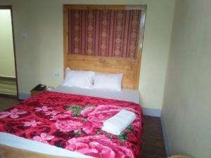 Schlafzimmer mit einem Bett mit rosa Rosen in der Unterkunft Shillong City Hotel in Shillong