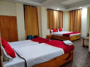 1 Schlafzimmer mit 2 Betten mit roter und weißer Bettwäsche in der Unterkunft Shillong City Hotel in Shillong