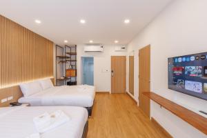 ein Hotelzimmer mit zwei Betten und einem Flachbildfernseher in der Unterkunft Believeinn in Bangkok