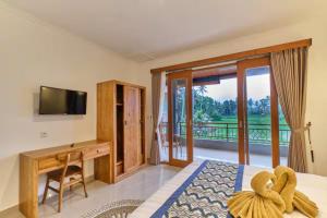 een slaapkamer met een bed, een bureau en een televisie bij Long Lane Bali Villa in Ubud