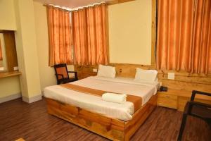 ein Schlafzimmer mit einem großen Holzbett mit 2 Stühlen in der Unterkunft Shillong City Hotel in Shillong