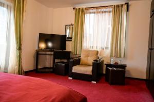 ein Hotelzimmer mit einem Stuhl und einem TV in der Unterkunft Casa Frent in Predeal