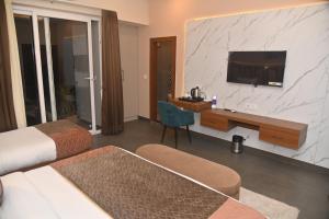 a hotel room with a bed and a desk with a television at Aarush Hotel & Resort in Haldwāni