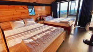 a bedroom with two beds and a large window at Đồi Mây Homestay Bảo Lộc in Bảo Lộc