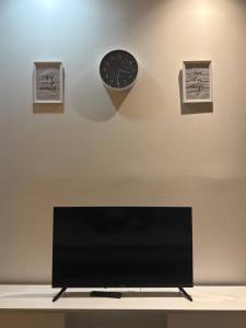 einen TV auf einem Tisch mit einer Uhr an der Wand in der Unterkunft Majestic Manhattan Suites ITCC in Penampang