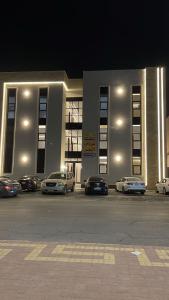 a building with cars parked in a parking lot at night at مارڤت للإيجار اليومي in Hafr Al-Batin